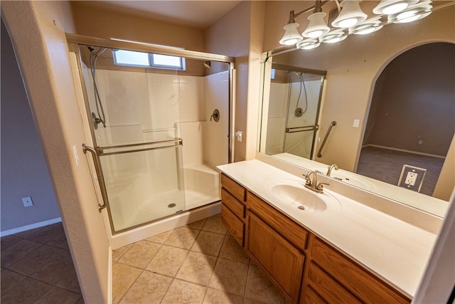 bathroom with a stall shower, vanity, tile patterned floors, and baseboards