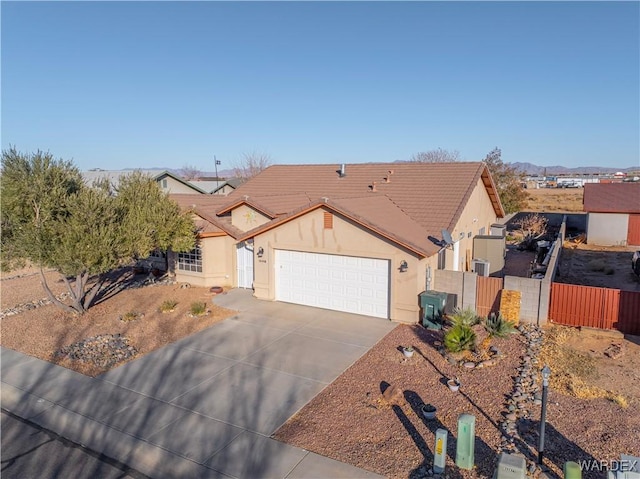 view of front of home with a garage, concrete driveway, fence, and stucco siding