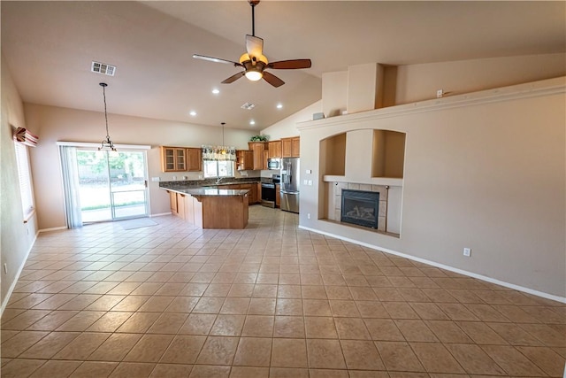 kitchen with appliances with stainless steel finishes, open floor plan, light tile patterned floors, dark countertops, and ceiling fan