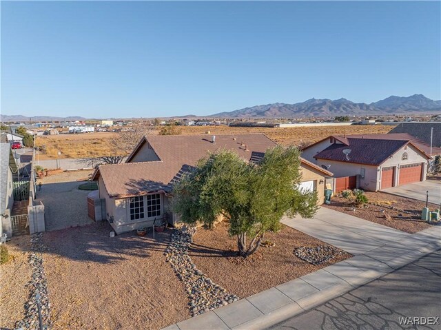 view of front facade featuring a garage, a mountain view, concrete driveway, and stucco siding