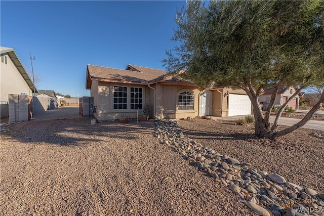 single story home featuring a garage, driveway, fence, and stucco siding