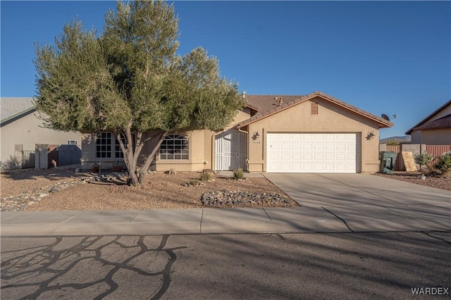 single story home with a garage, concrete driveway, a tile roof, and stucco siding