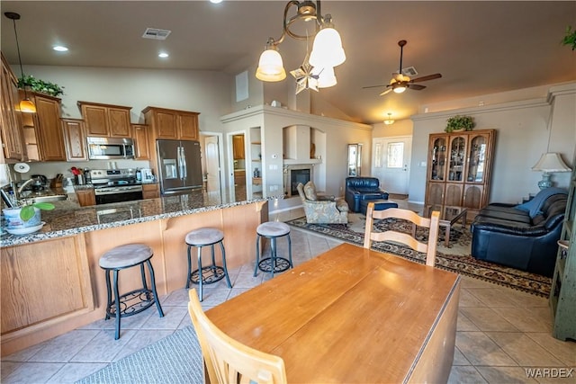 kitchen featuring stainless steel appliances, a peninsula, visible vents, open floor plan, and dark stone counters