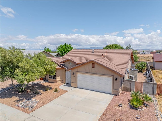 view of front facade featuring a tiled roof, a garage, stucco siding, fence, and driveway
