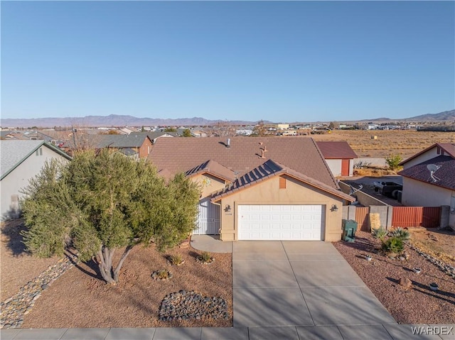 view of front of house featuring an attached garage, a mountain view, concrete driveway, a residential view, and stucco siding