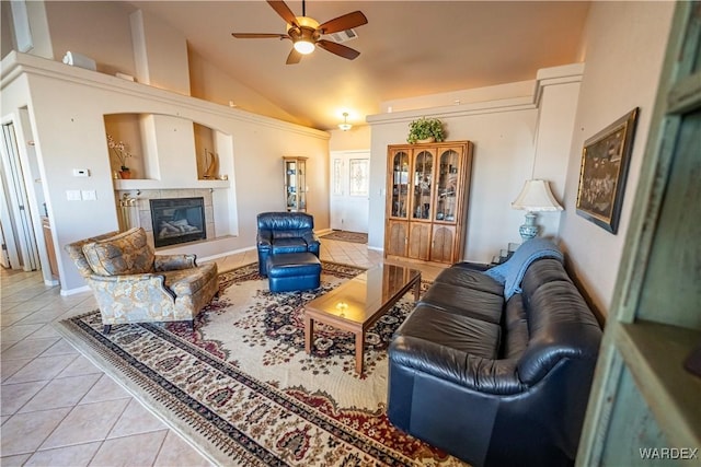 living room featuring a ceiling fan, vaulted ceiling, a fireplace, and light tile patterned floors