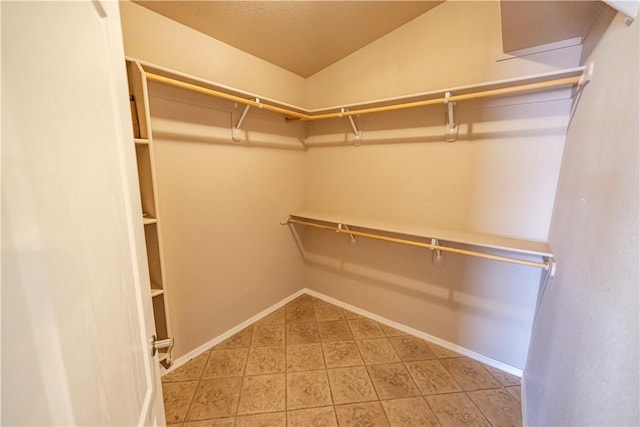 spacious closet featuring light tile patterned floors and lofted ceiling