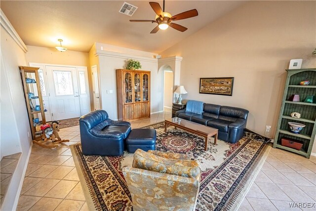 living area featuring lofted ceiling, light tile patterned floors, visible vents, and a ceiling fan