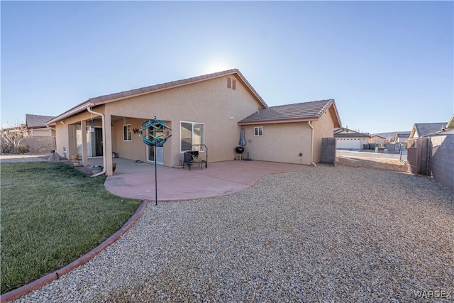 back of house featuring fence, a tile roof, a yard, stucco siding, and a patio area