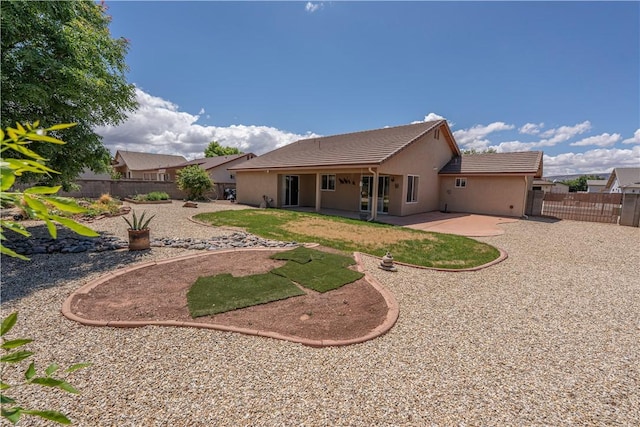 back of house featuring stucco siding, fence, a patio, and a tiled roof