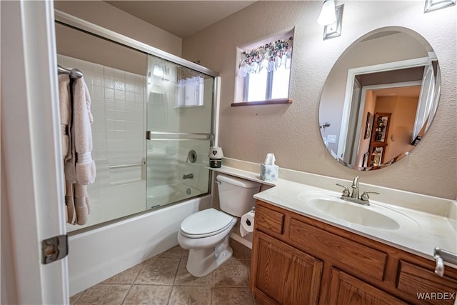 full bath with a textured wall, tile patterned flooring, toilet, bath / shower combo with glass door, and vanity