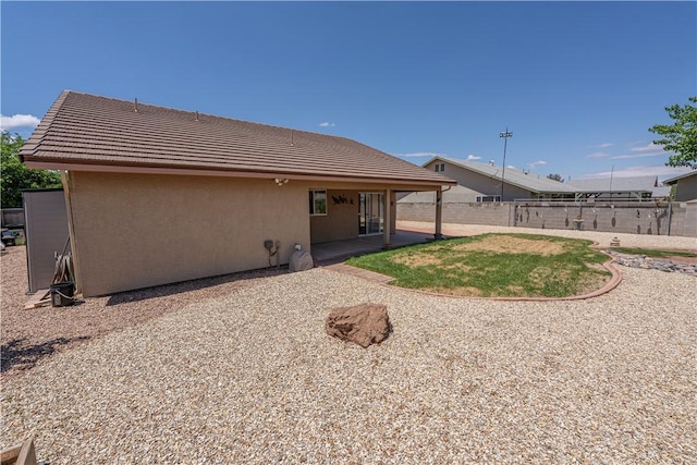 rear view of property with stucco siding, fence, a tile roof, and a patio