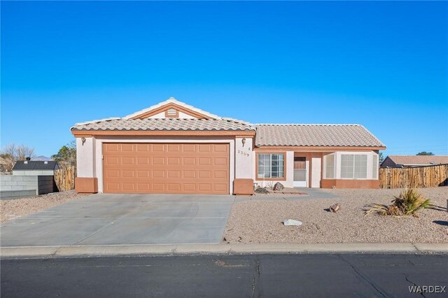 view of front of property featuring an attached garage, a tile roof, concrete driveway, and stucco siding