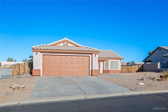 view of front facade featuring concrete driveway, a tile roof, an attached garage, and stucco siding