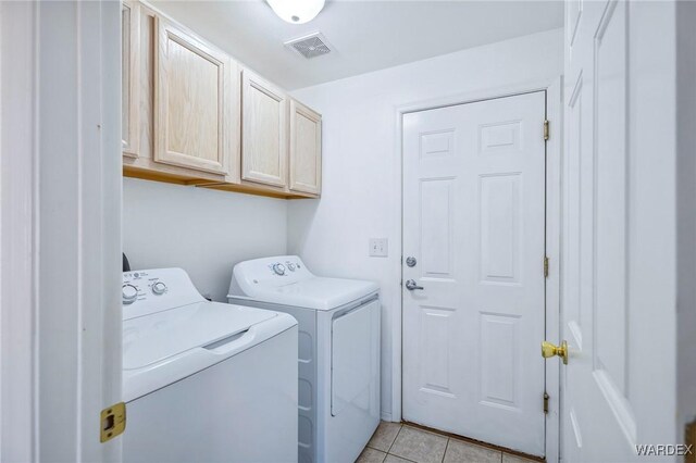 laundry area featuring visible vents, separate washer and dryer, light tile patterned flooring, and cabinet space