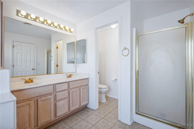 bathroom featuring a stall shower, double vanity, a sink, and tile patterned floors