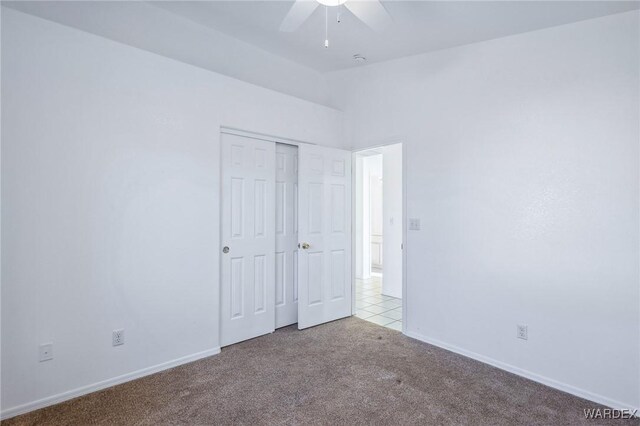 unfurnished bedroom with light carpet, baseboards, lofted ceiling, ceiling fan, and a closet