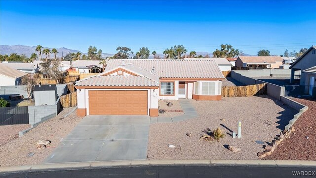 view of front of property with concrete driveway, stucco siding, a tile roof, and fence