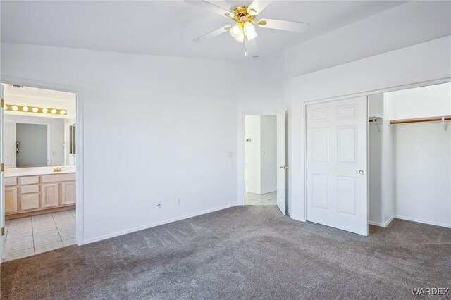 unfurnished bedroom with a closet, light carpet, ceiling fan, and ensuite bathroom