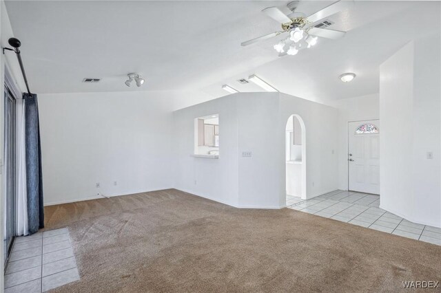 spare room with arched walkways, lofted ceiling, light colored carpet, and visible vents