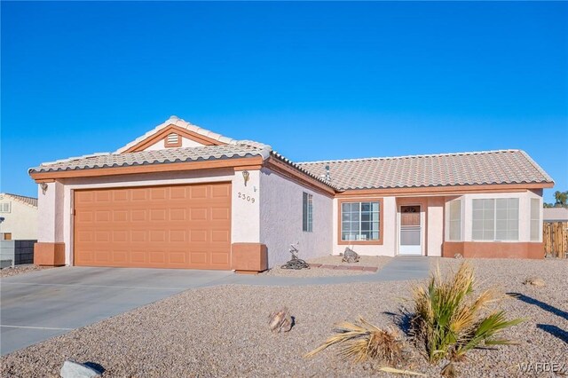 view of front of home featuring concrete driveway, a tile roof, an attached garage, and stucco siding