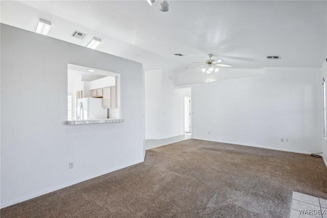 spare room with ceiling fan, carpet, lofted ceiling, and visible vents