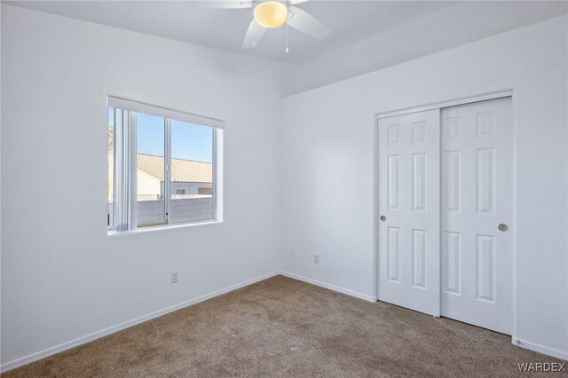 unfurnished bedroom featuring light carpet, ceiling fan, baseboards, and a closet