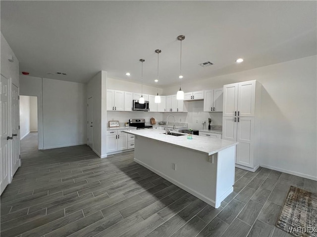 kitchen with a kitchen island with sink, stainless steel appliances, visible vents, white cabinets, and wood tiled floor