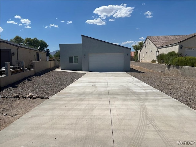 view of front of house with an attached garage, fence, concrete driveway, and stucco siding