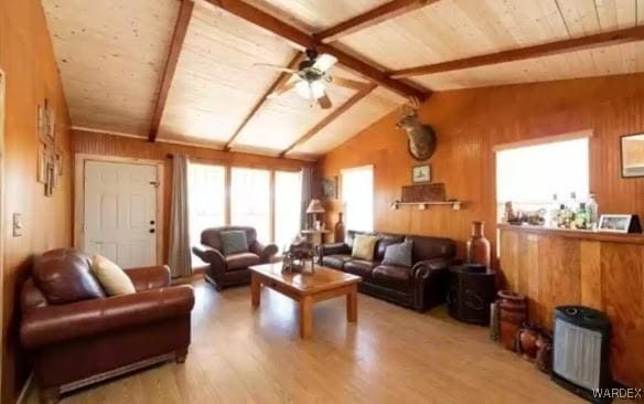 living room featuring vaulted ceiling with beams, wooden walls, wood ceiling, light wood-style floors, and a ceiling fan