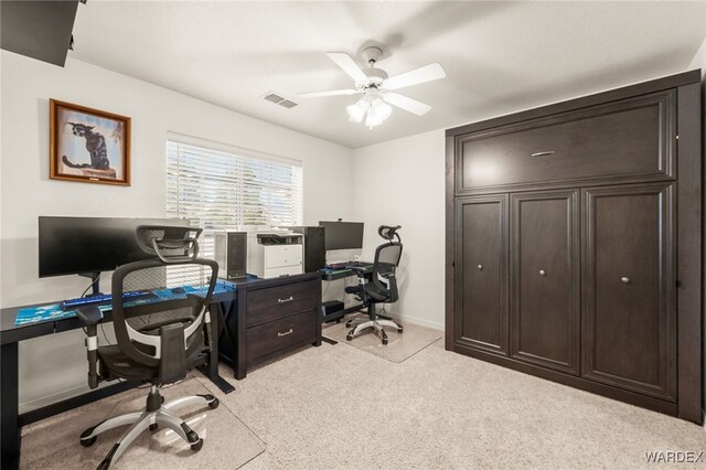 office featuring a ceiling fan, light colored carpet, visible vents, and baseboards