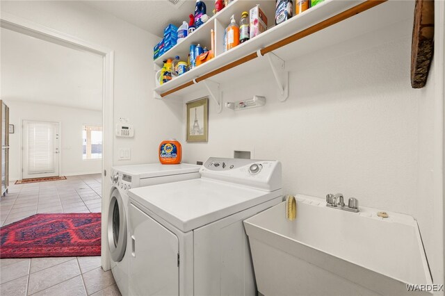 laundry area featuring light tile patterned floors, laundry area, baseboards, independent washer and dryer, and a sink