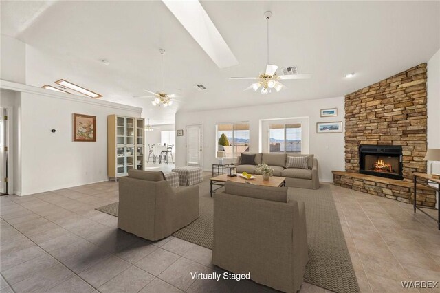 tiled living area featuring a fireplace, lofted ceiling, visible vents, ceiling fan, and baseboards