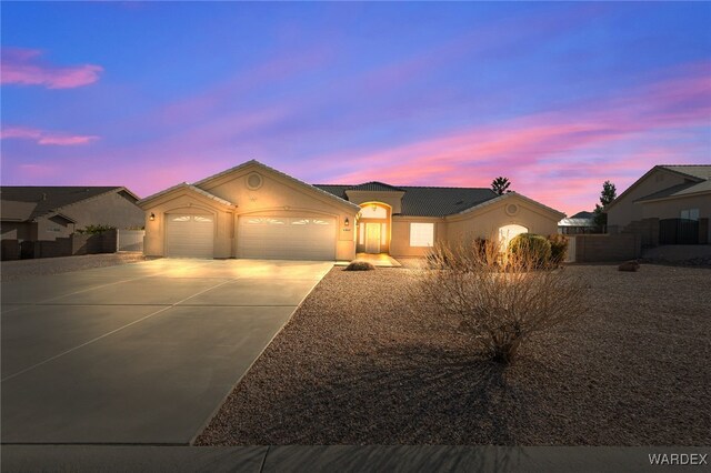 view of front of house with driveway, an attached garage, and stucco siding