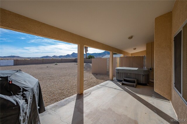 view of patio / terrace featuring grilling area, a fenced backyard, a mountain view, and a hot tub