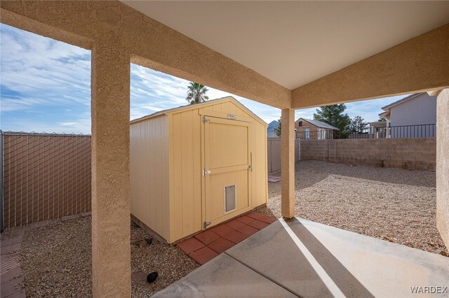 view of patio with a fenced backyard, a storage unit, and an outbuilding