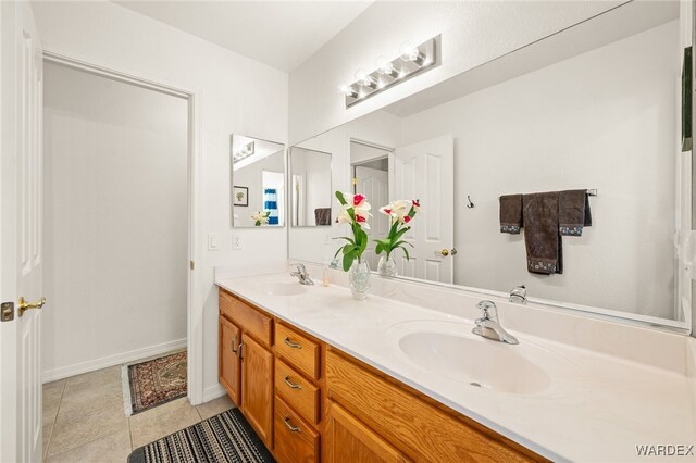 bathroom featuring tile patterned flooring, a sink, baseboards, and double vanity