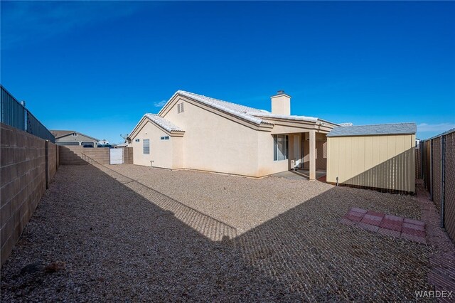 back of property featuring a fenced backyard, a chimney, and stucco siding