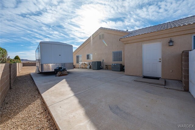 back of property with a tile roof, a patio area, a fenced backyard, and stucco siding