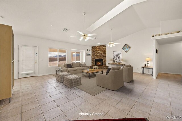 living room featuring visible vents, a ceiling fan, light tile patterned flooring, vaulted ceiling, and a stone fireplace