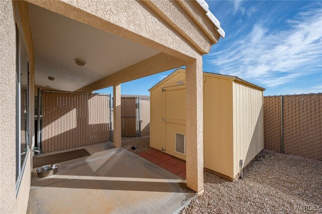 view of patio with an outdoor structure, a gate, fence, and a storage shed