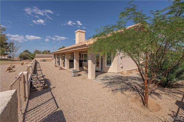 back of house featuring a chimney, fence, a patio, and stucco siding