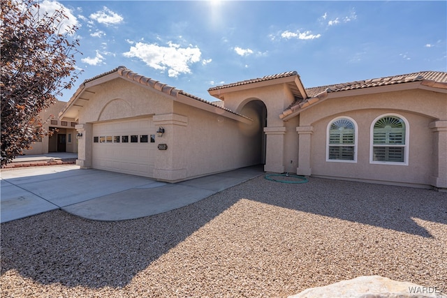 mediterranean / spanish-style house with a garage, concrete driveway, and stucco siding