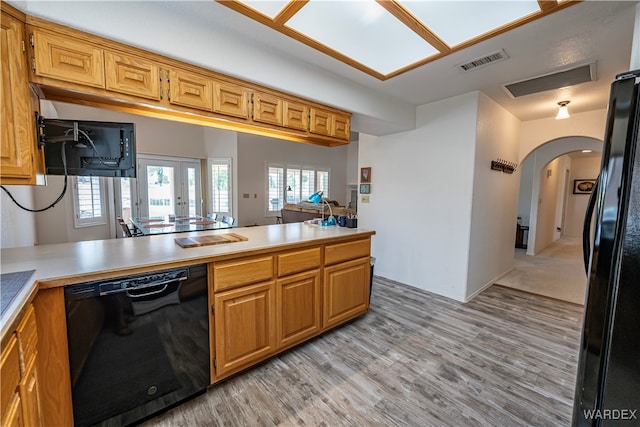 kitchen with brown cabinets, light countertops, visible vents, a peninsula, and black appliances