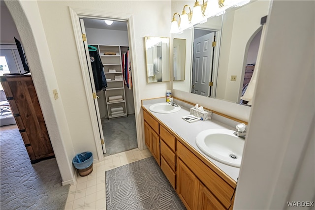 bathroom featuring double vanity, tile patterned flooring, a walk in closet, and a sink