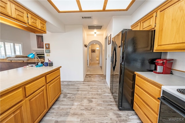 kitchen with arched walkways, light countertops, visible vents, and light wood finished floors