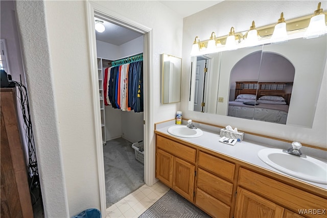 bathroom featuring a sink, a spacious closet, and double vanity