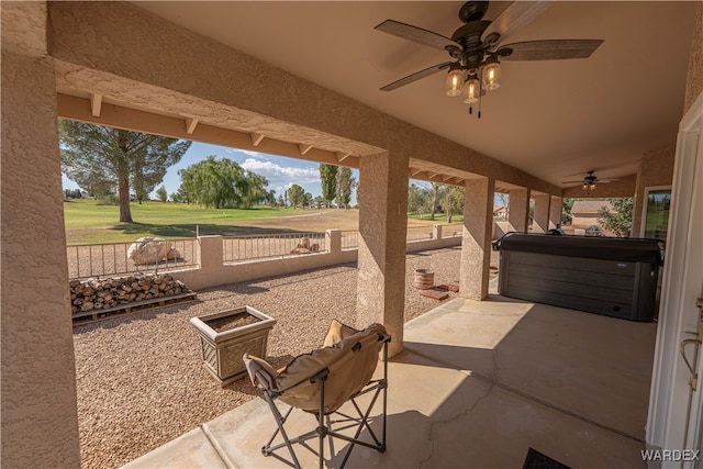 view of patio featuring a ceiling fan, a fenced backyard, and a hot tub