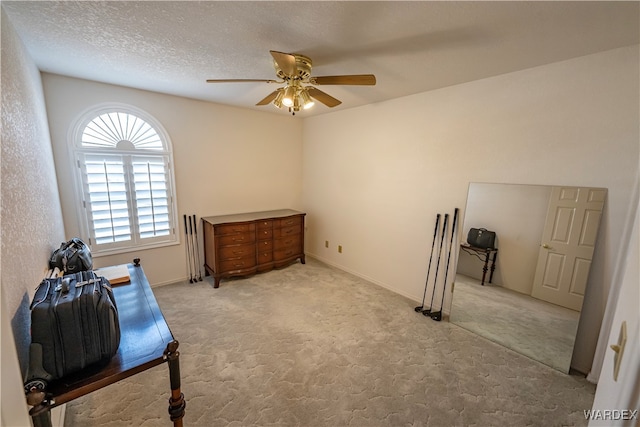 sitting room with light carpet, a textured ceiling, a ceiling fan, and baseboards