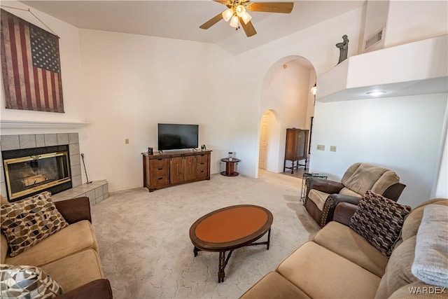 living area with visible vents, arched walkways, a ceiling fan, light colored carpet, and a fireplace